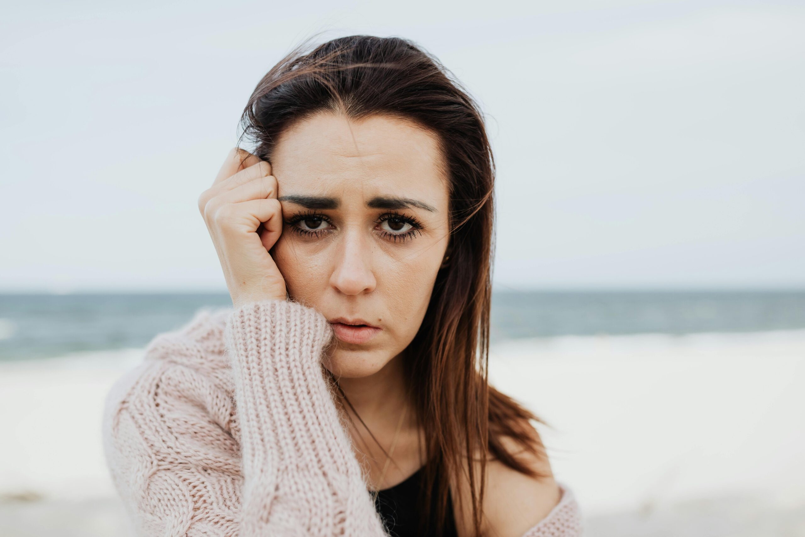 Mujer con gesto reflexivo representando la gestión emocional y el afrontamiento psicológico del dolor crónico.