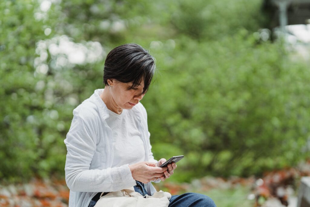 Mujer mirando el móvil en un entorno exterior, concepto de apoyo emocional digital, terapia online e IA aplicada a la salud mental.