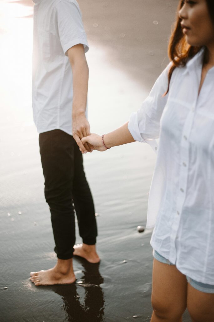 Pareja caminando de la mano junto al mar, imagen de distancia emocional y bloqueo o silencio en la relación de pareja.