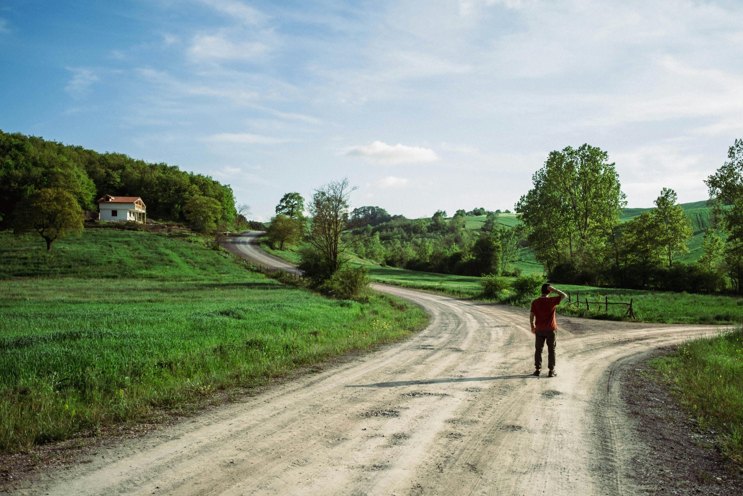Persona ante un cruce de caminos en la naturaleza, metáfora de decidir sin certezas y avanzar pese a la incertidumbre.