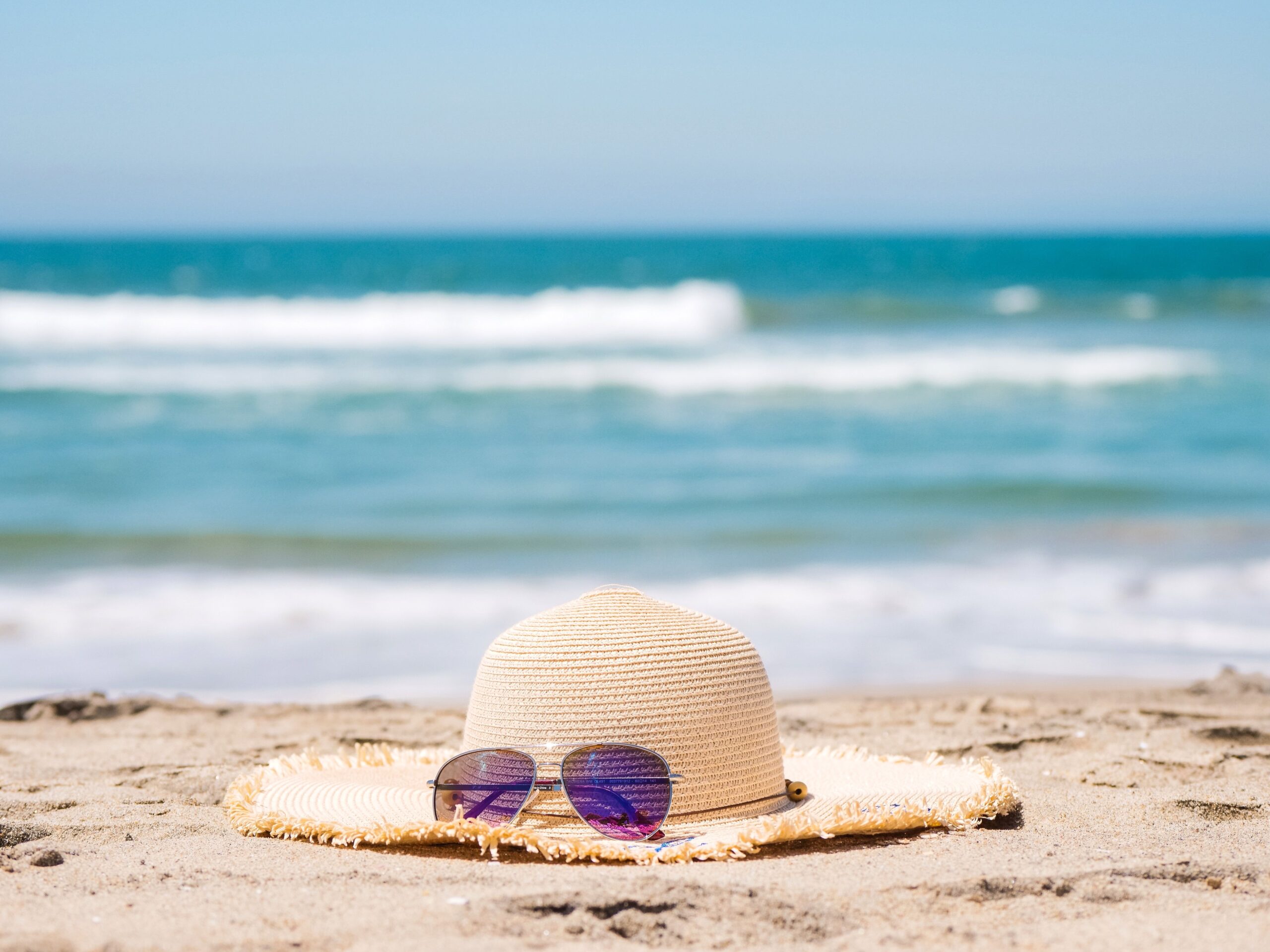 Sombrero y gafas de sol en la playa, imagen sobre vacaciones, descanso y convivencia en pareja durante el verano.